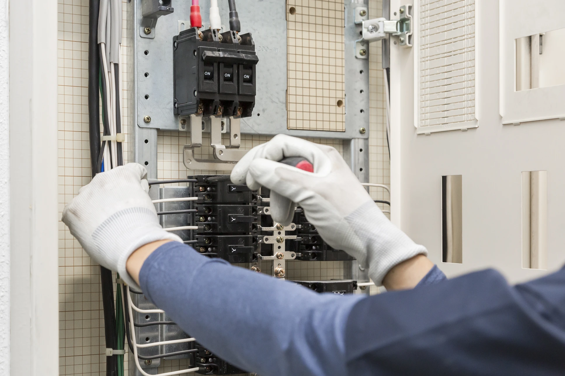 Service d'entretien de l'électricité et de l'électricité, ingénieur utilisant un outil de mesure de l'équipement pour vérifier la tension du courant électrique au terminal de disjoncteur et à la carte principale de distribution de l'énergie du câblage